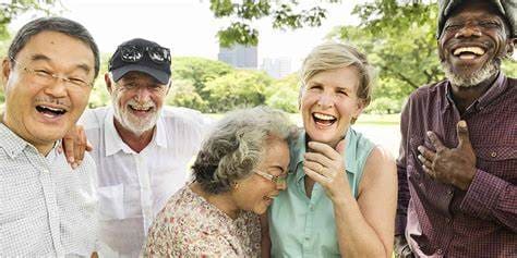 Five older adults laughing together outdoors