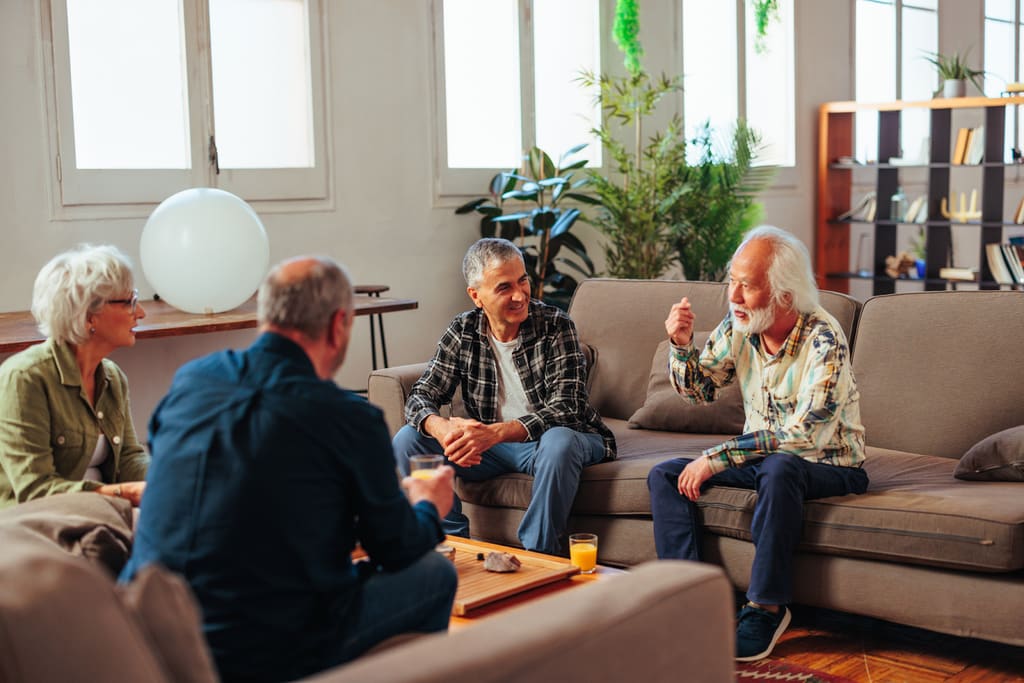 Four older adults talking together in a living room