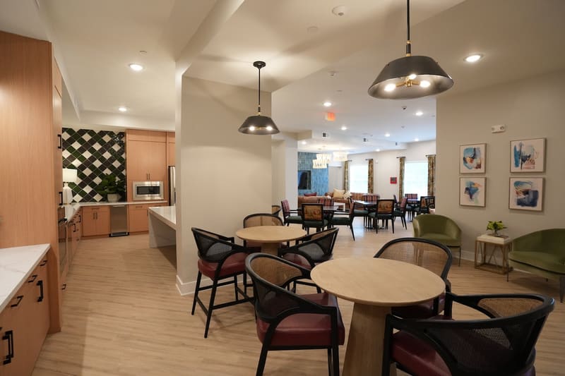 Clubroom dining tables beside the kitchen and lounge
