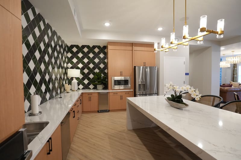 Clubroom kitchen with marble-look counters and stainless refrigerator