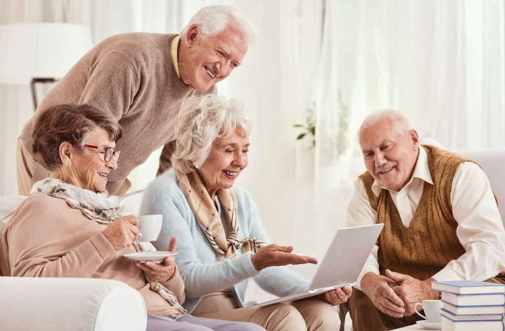 Four older adults looking at a laptop together